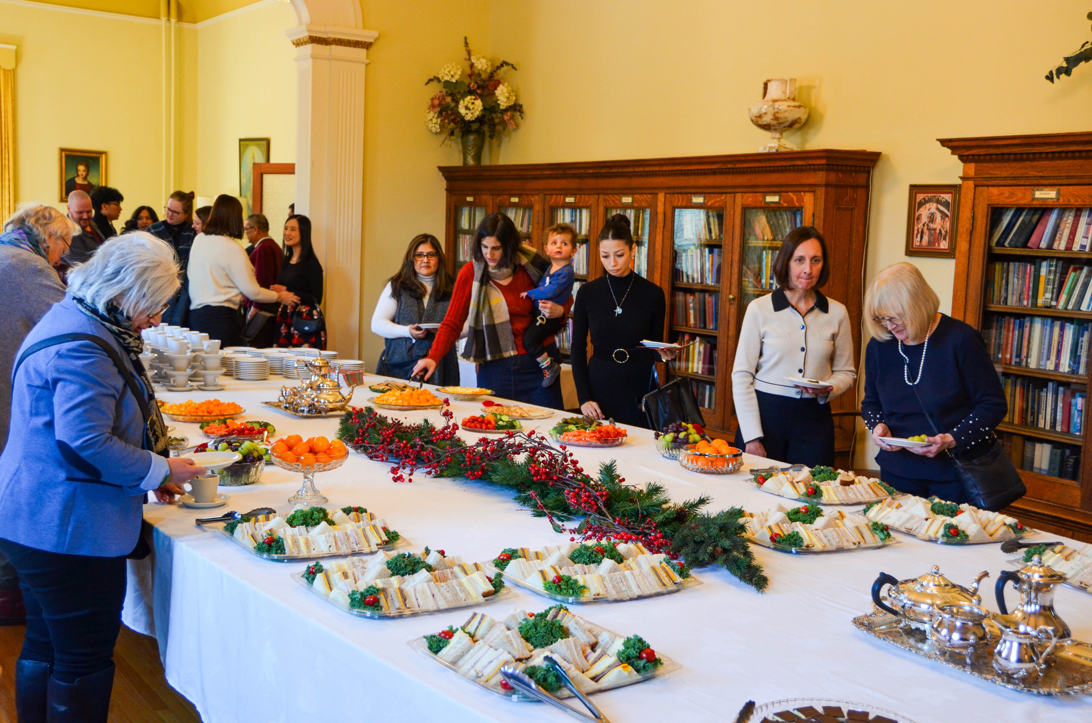 a group of people lining up and getting food on a long table.