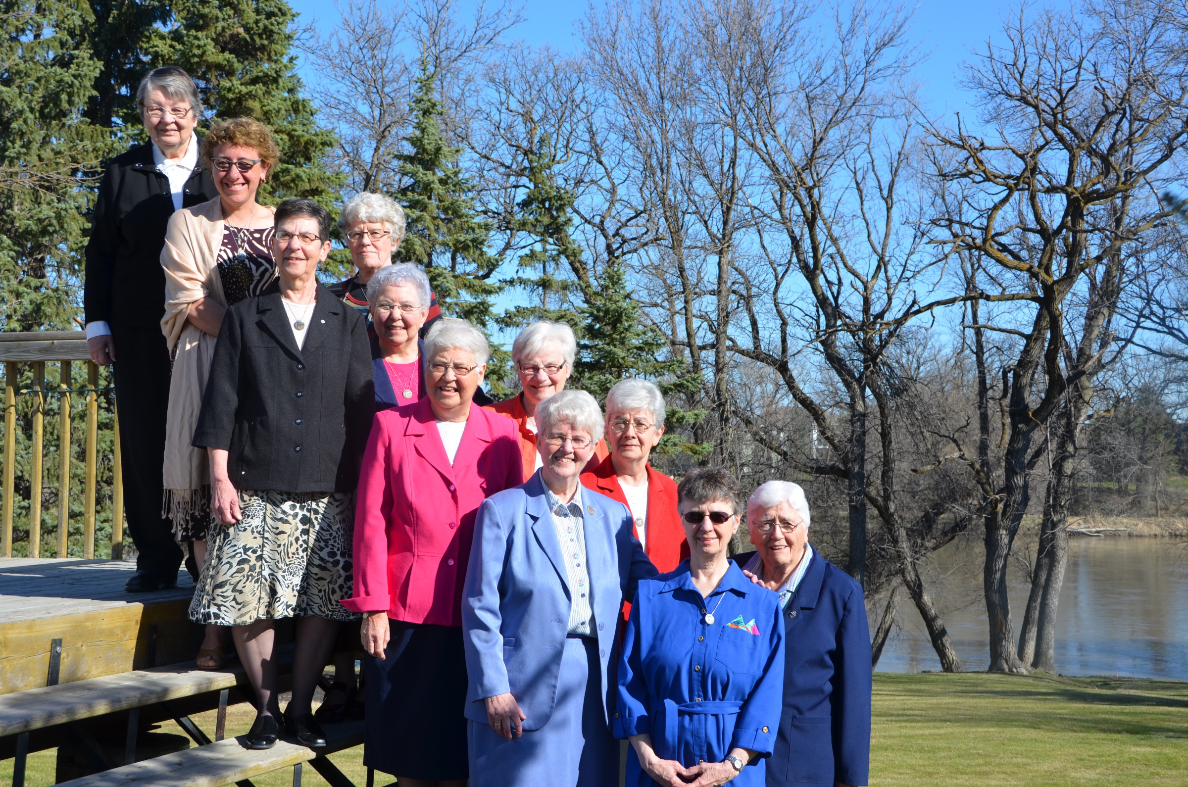a group photo of the Sisters of the Holy Names of Jesus and Mary standing on an outdoor staircase with tree in the background.