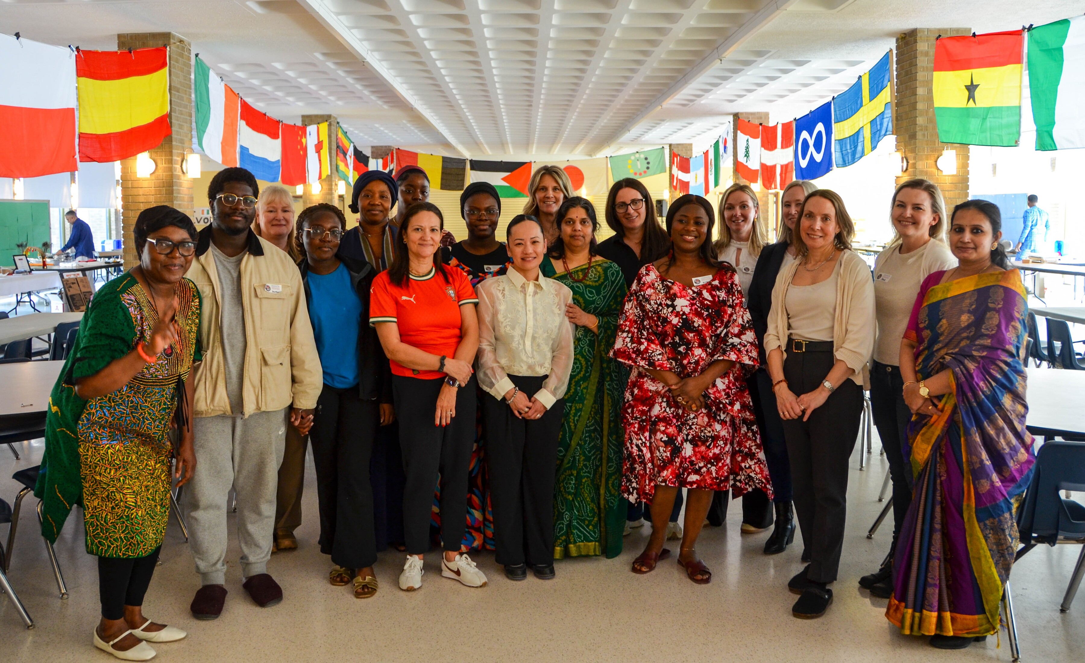 A group of people standing for group photo with different flags hanging in the background