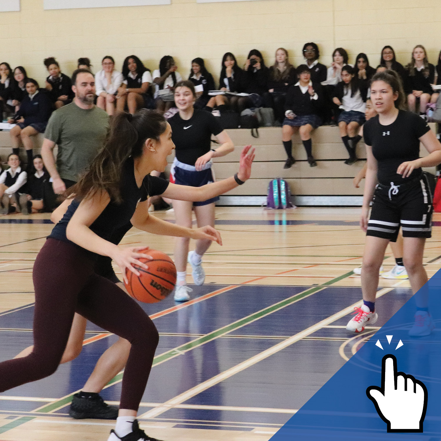 a group of students playing basketball with a male teacher in the background.