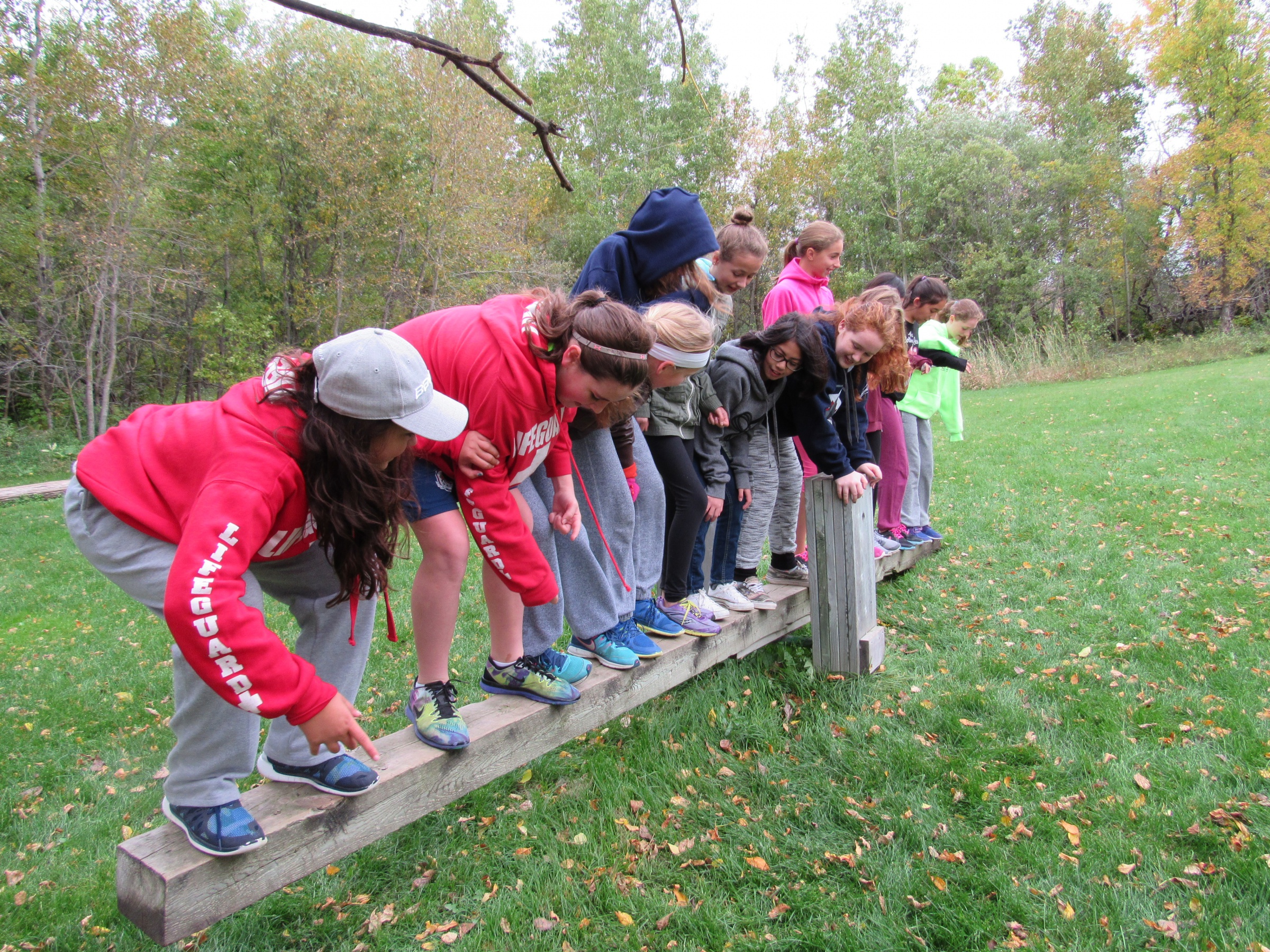 a group of students on casual clothing standing on a long piece of lumber