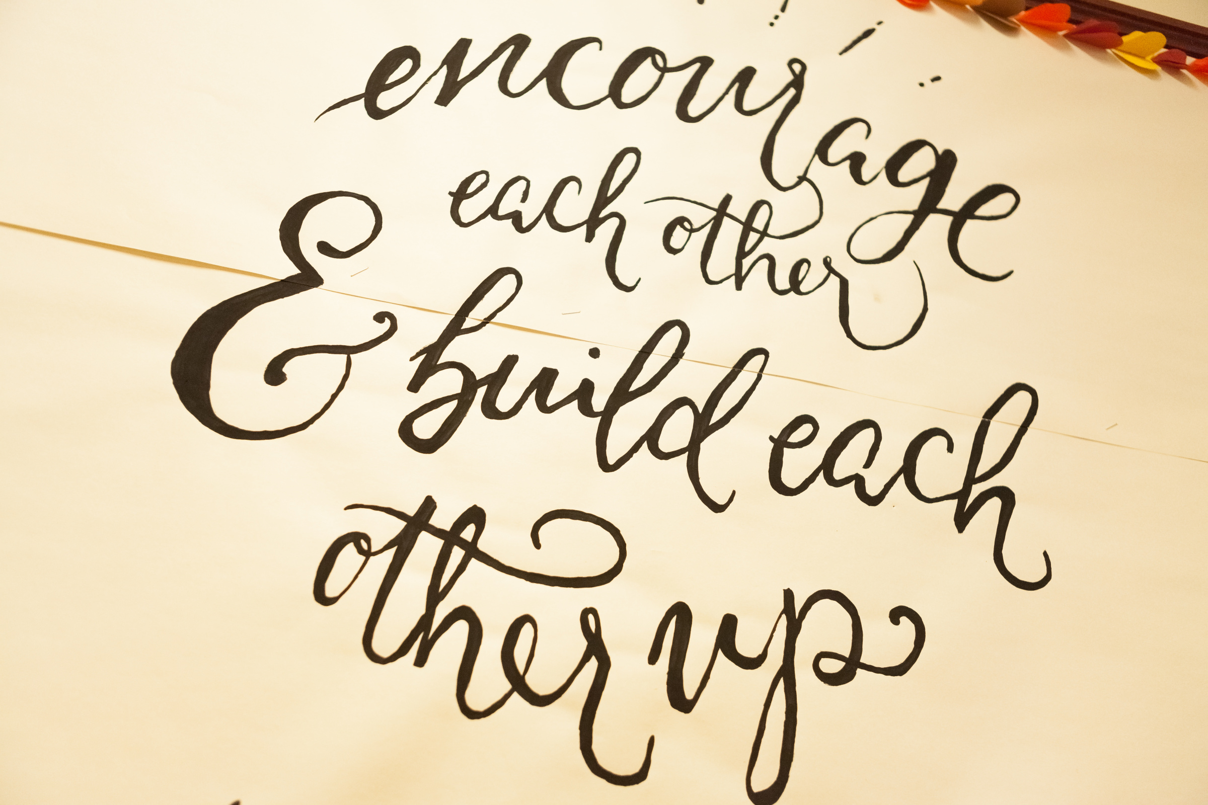 Decorative image that reads 'Encourage each other and build each other up' in flowy font.