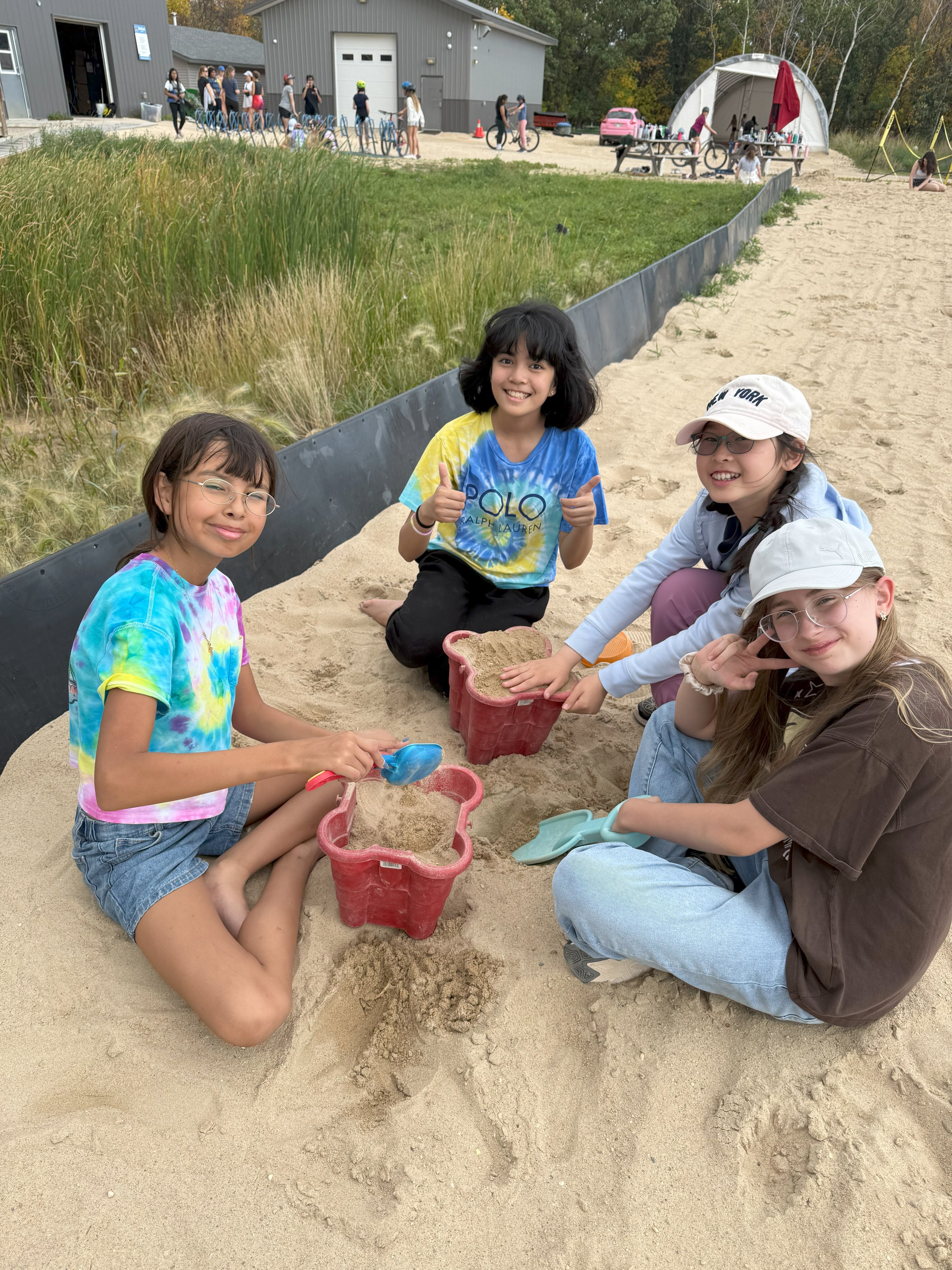 Four students sitting and playing with sand.