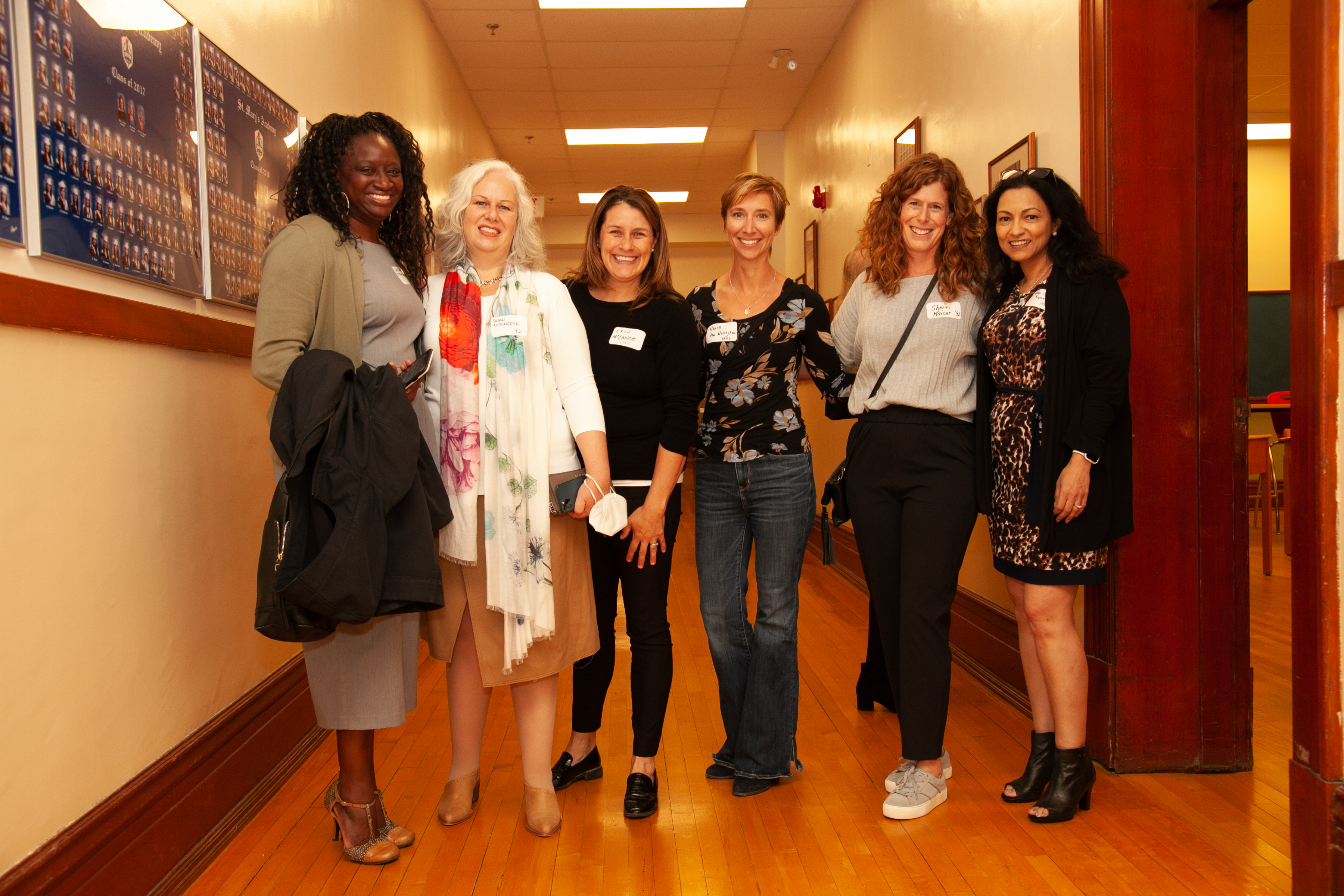 A group of six happy St. Mary's Academy alumnae stand in the hallway.