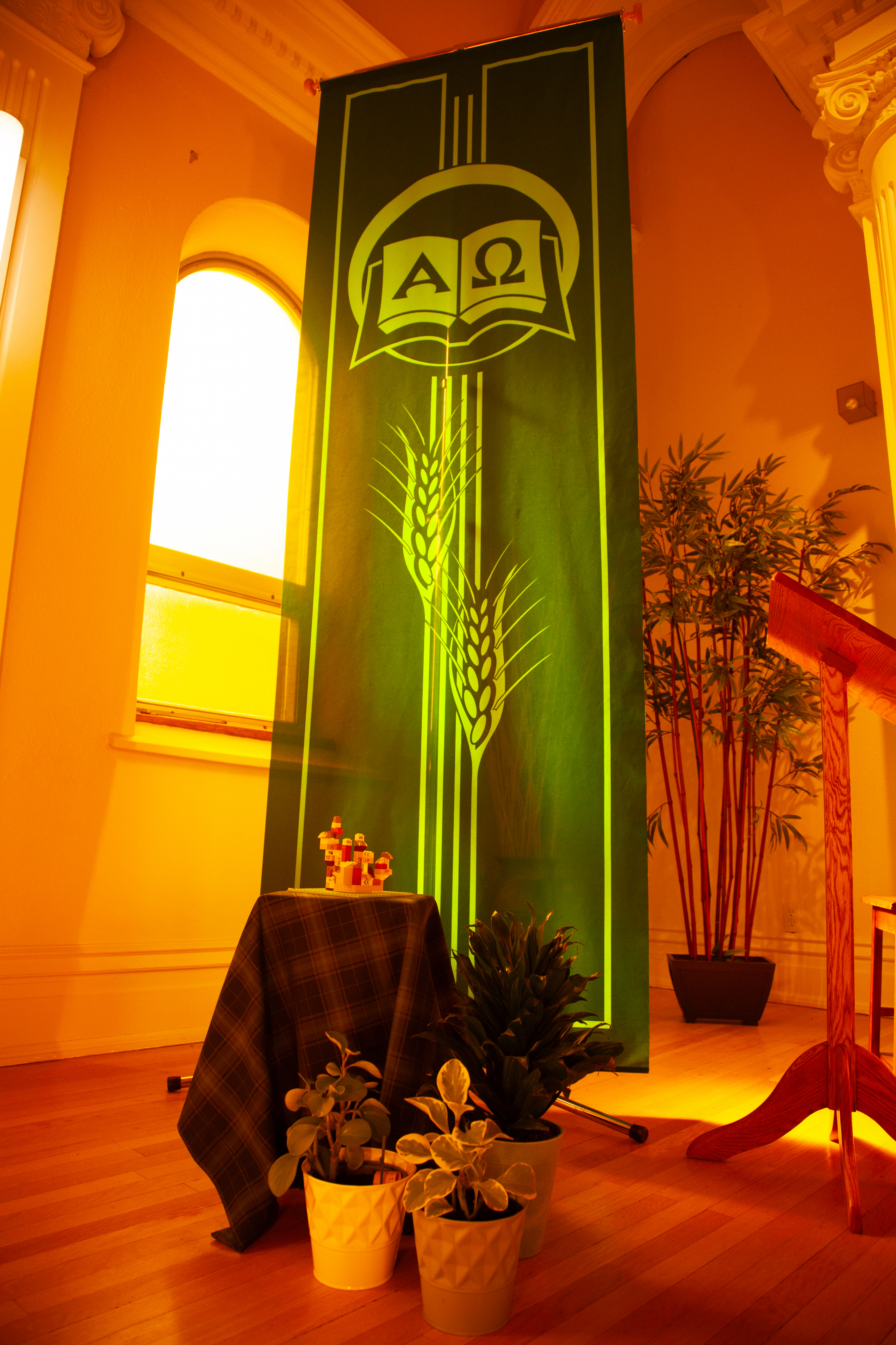 a green vertical fabric banner with religous decorative design and potted plants on the front