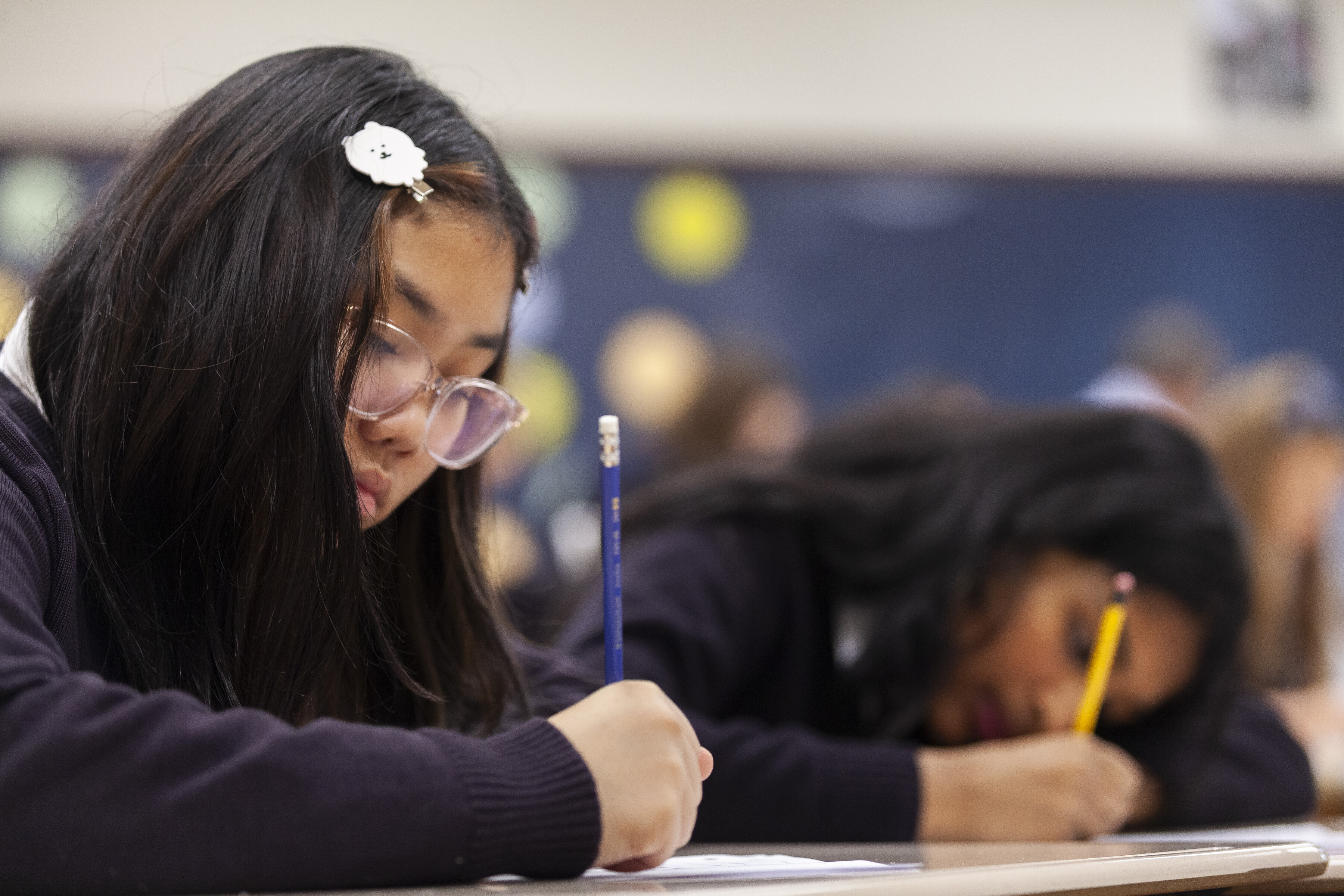 Two St. Mary's Academy students studying in class and writing with a pencil