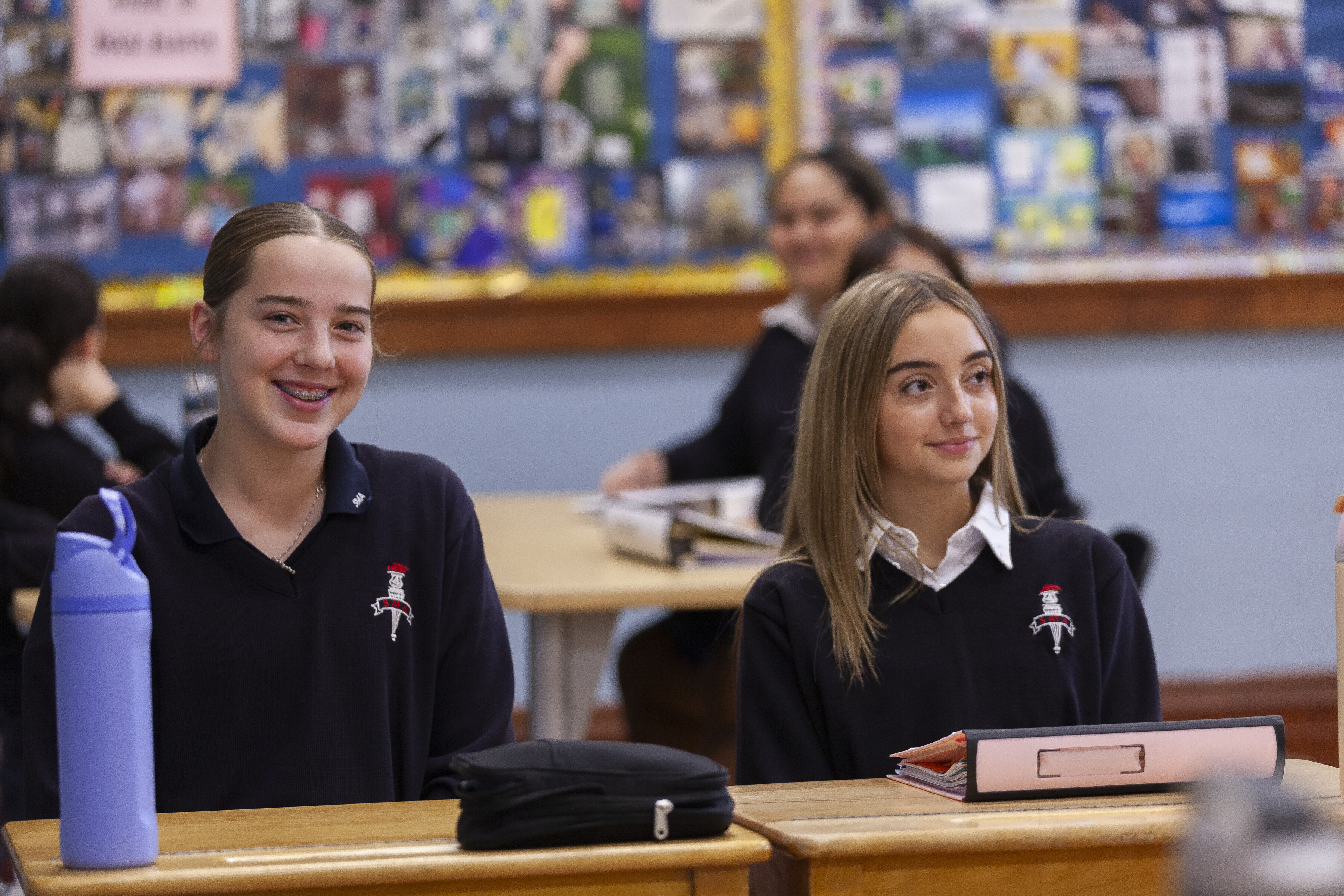 Two St. Mary's Academy students smiling while sitting in a classroom.