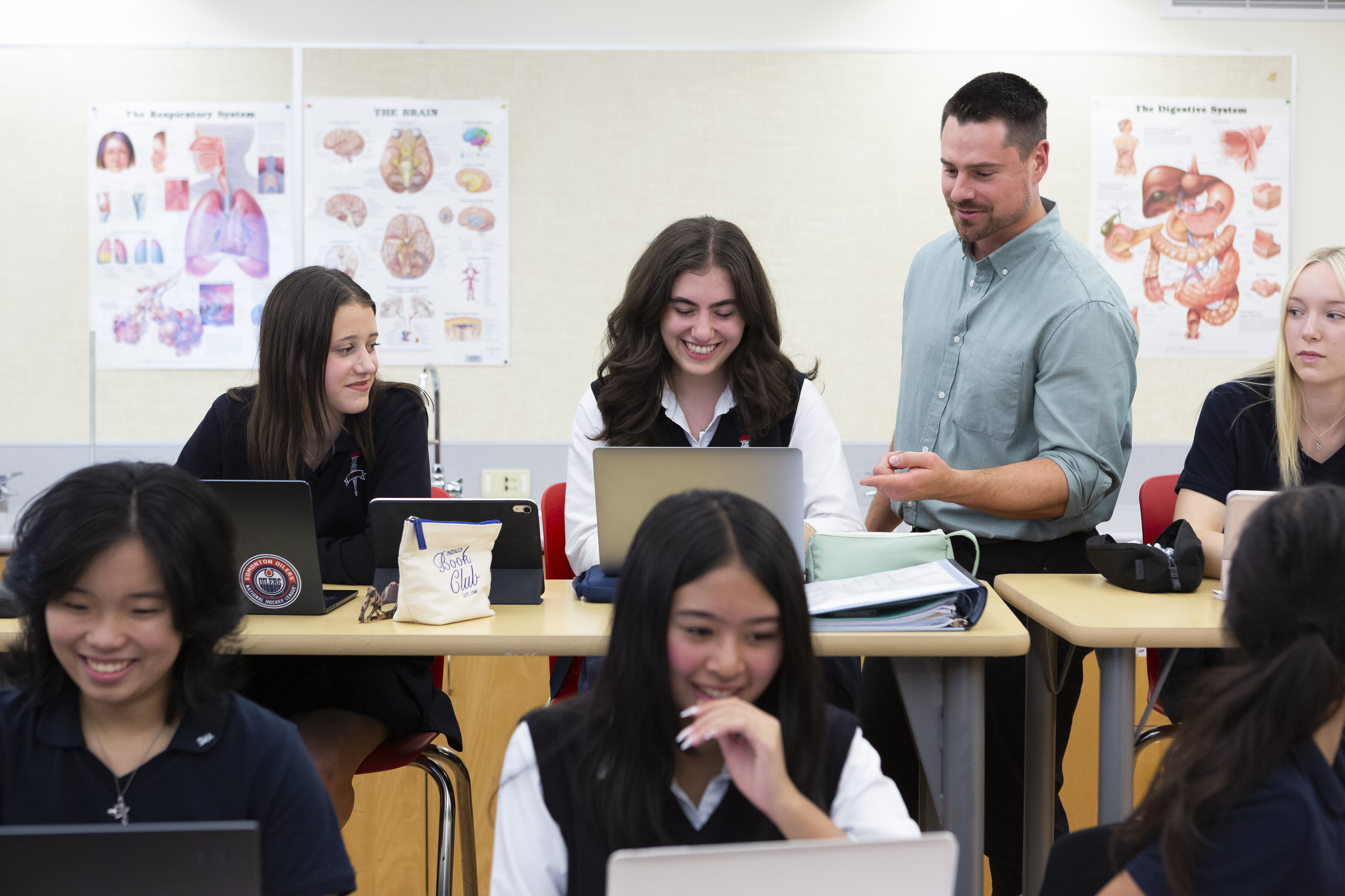 a group of SMA students studying and smiling together with a teacher nearby talking to them.