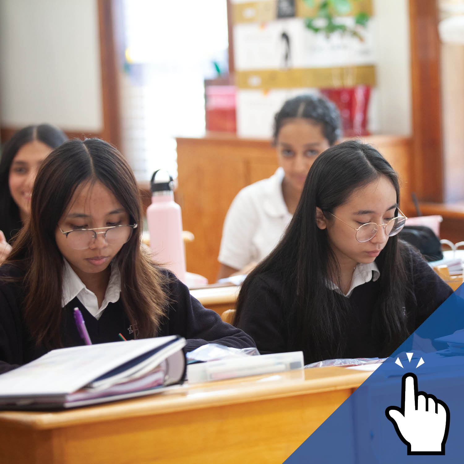 St. Mary's Academy students in uniform look down at their desk in a classroom.