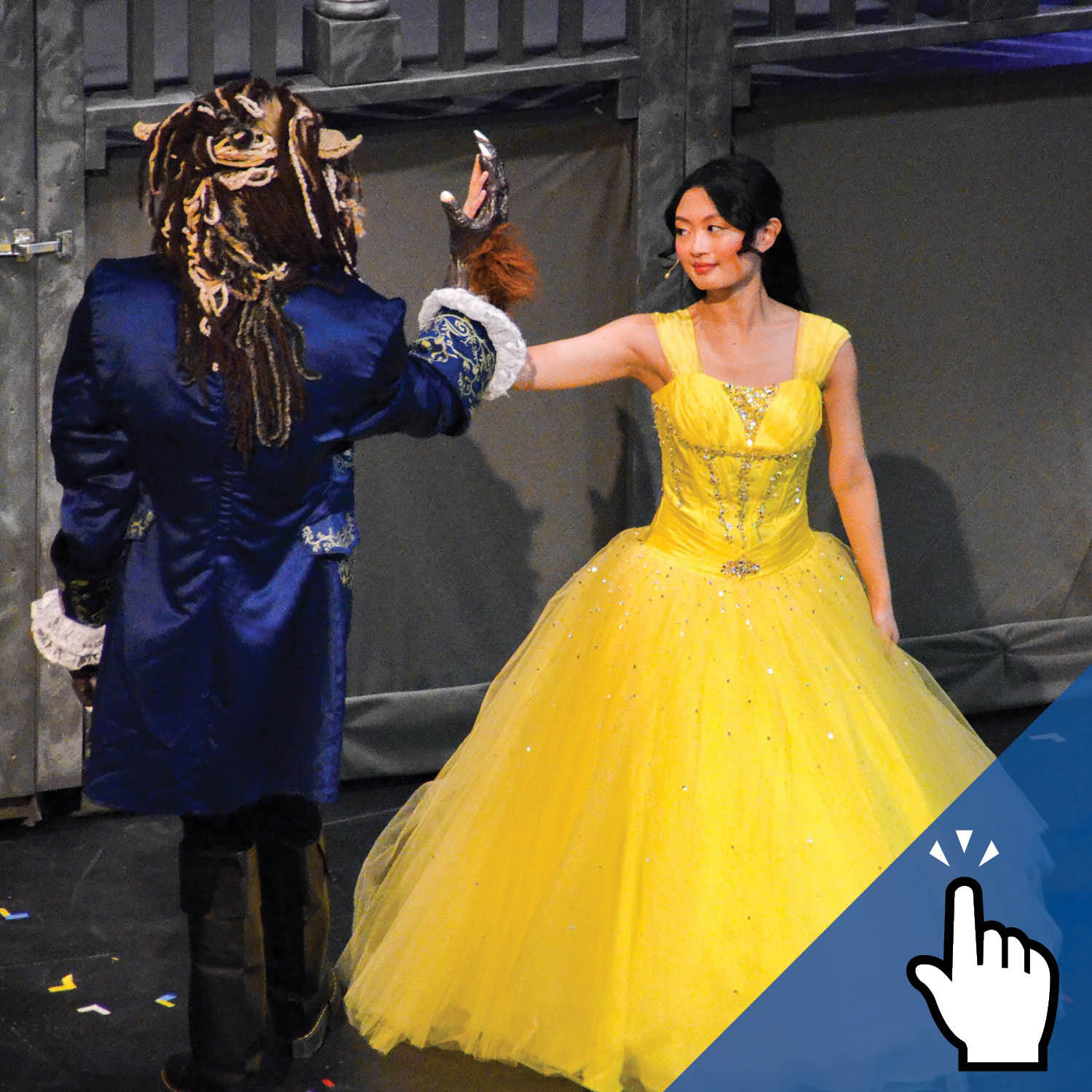 Two students dressed in Beauty and the Beast costumes stand on stage.