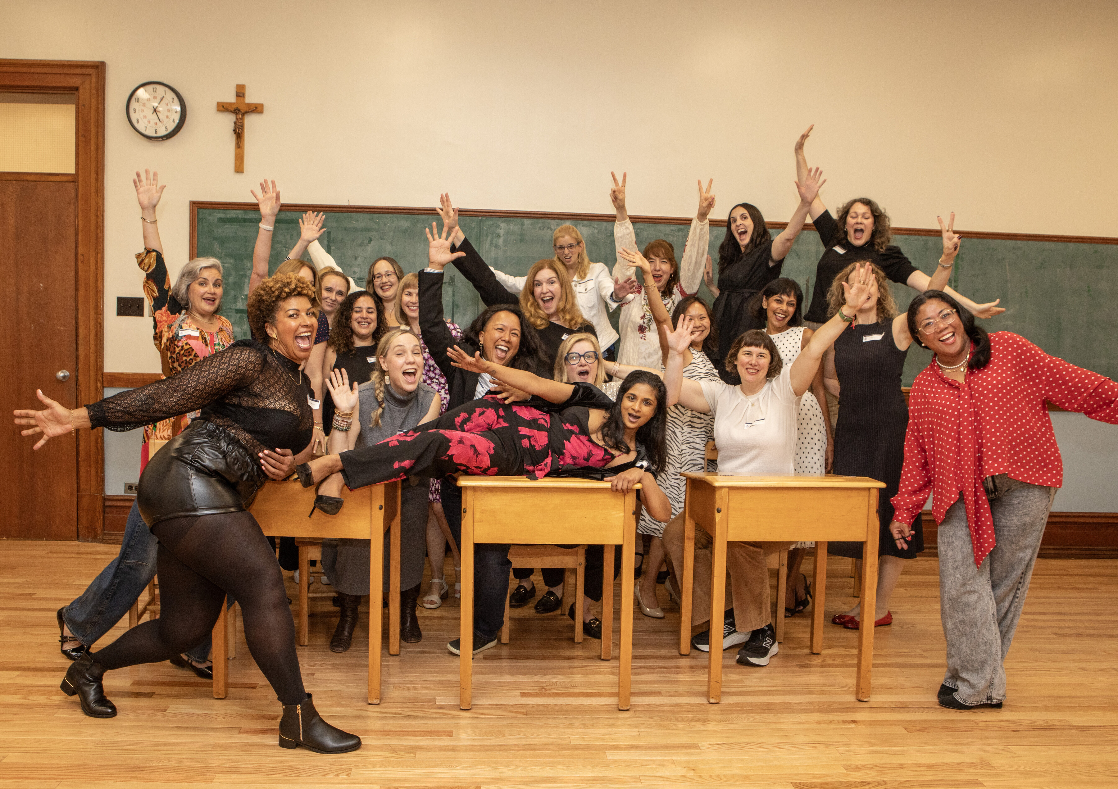Seven smiling alumnae stand and sit at a table in the St. Mary's Academy atrium.